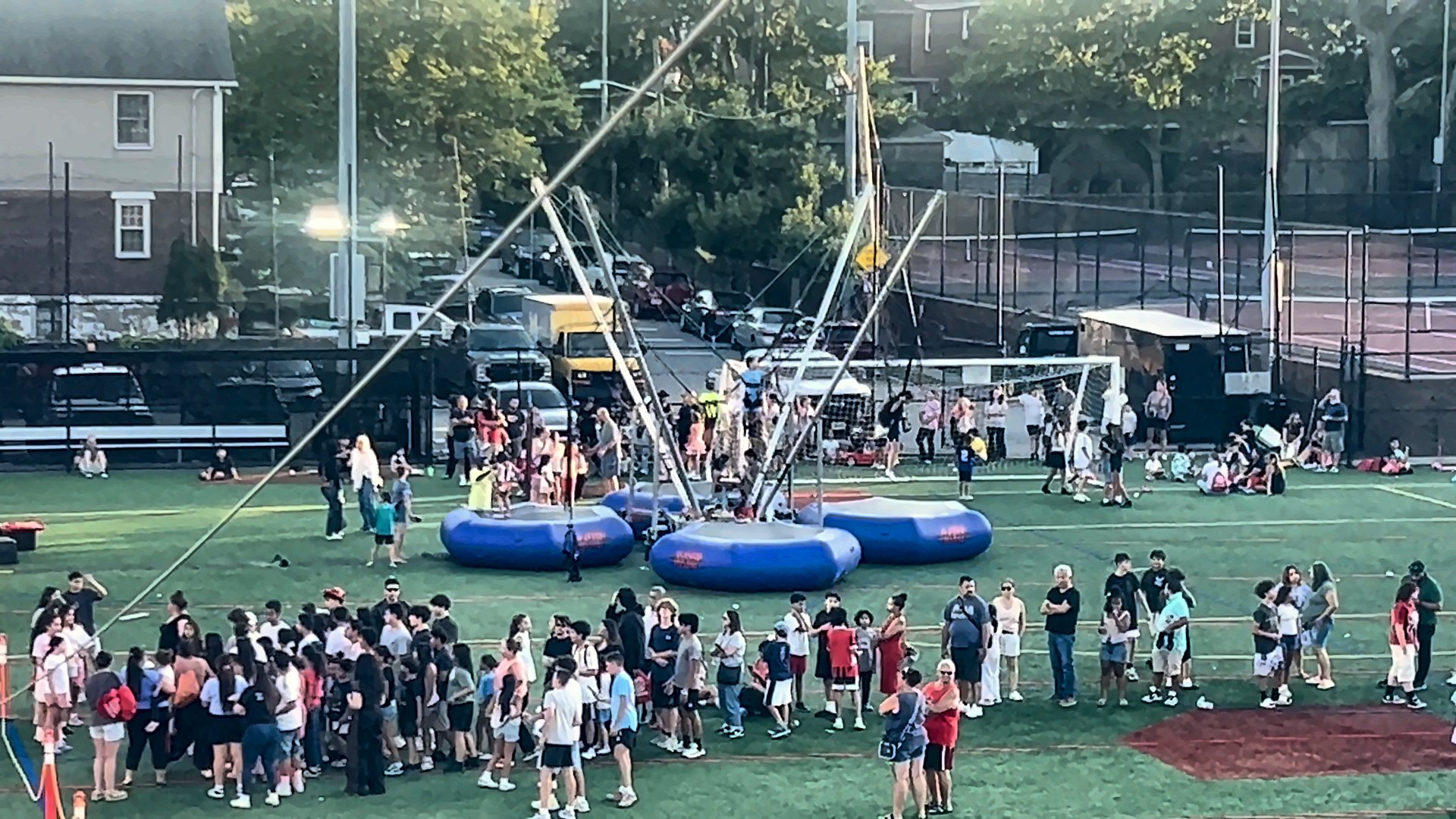 Crowd lined up for a four-station bungee trampoline at a township event